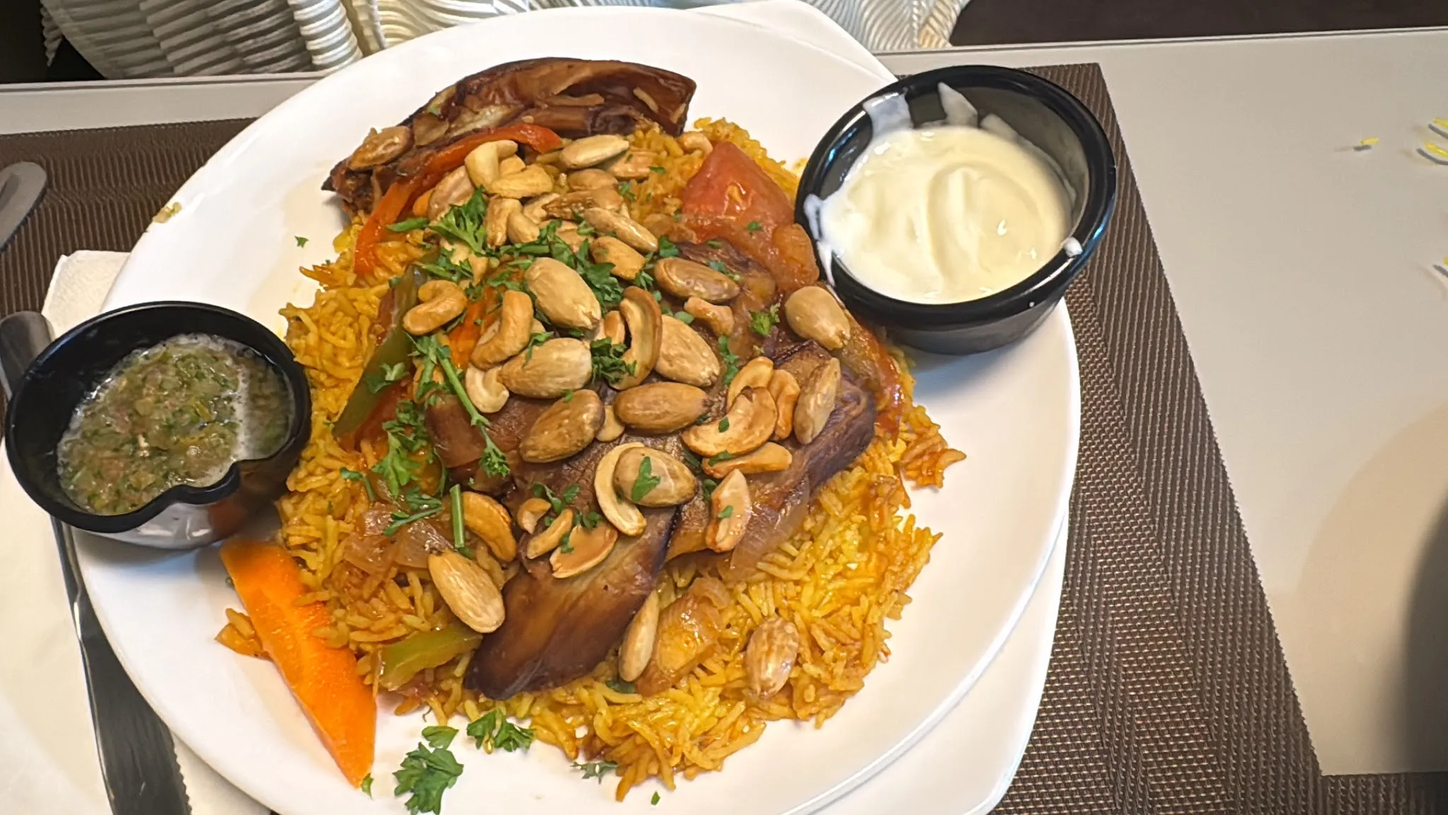 Lamb mandi platter — spiced rice topped with roast lamb, cashews and almonds, with yogurt and salsa