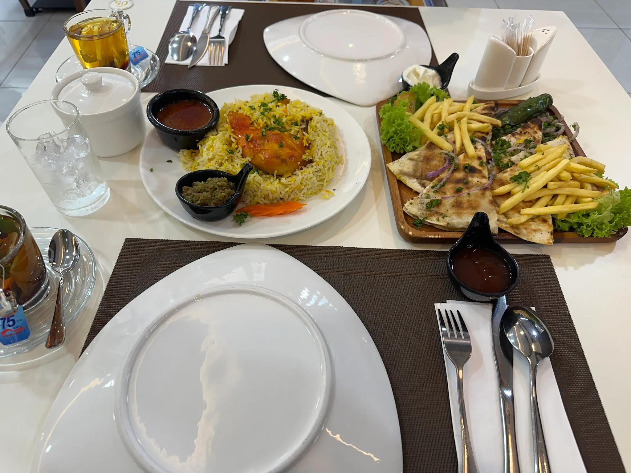 Table spread with a chicken and spiced rice plate and a tray of grilled flatbread with fries
