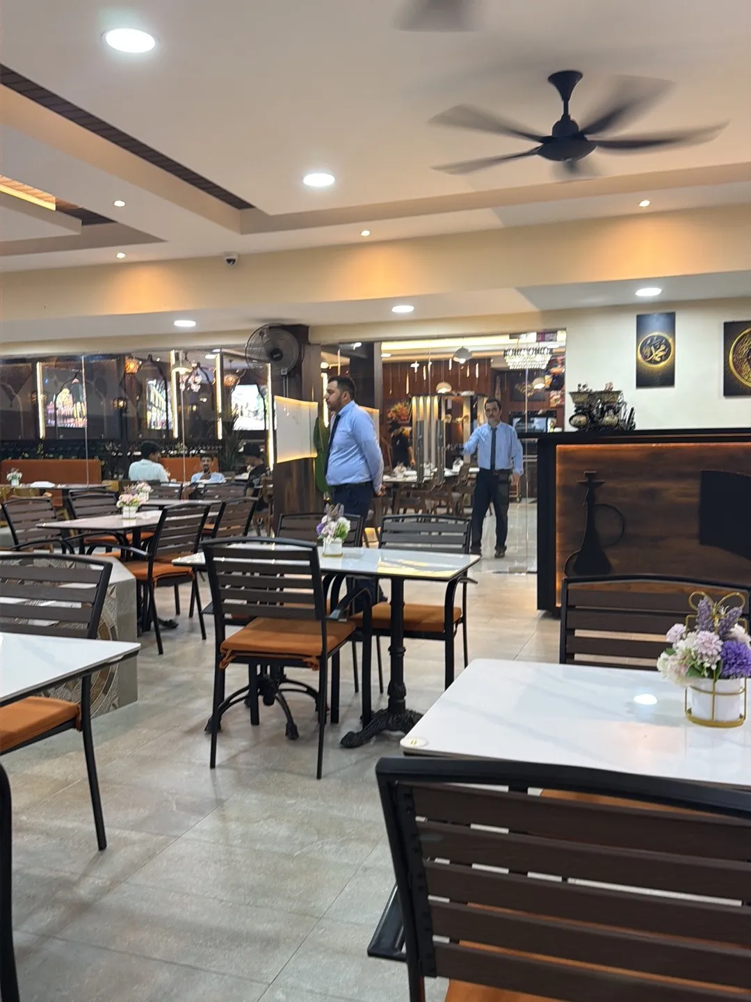 Main dining hall with marble-top tables and a shisha-motif counter