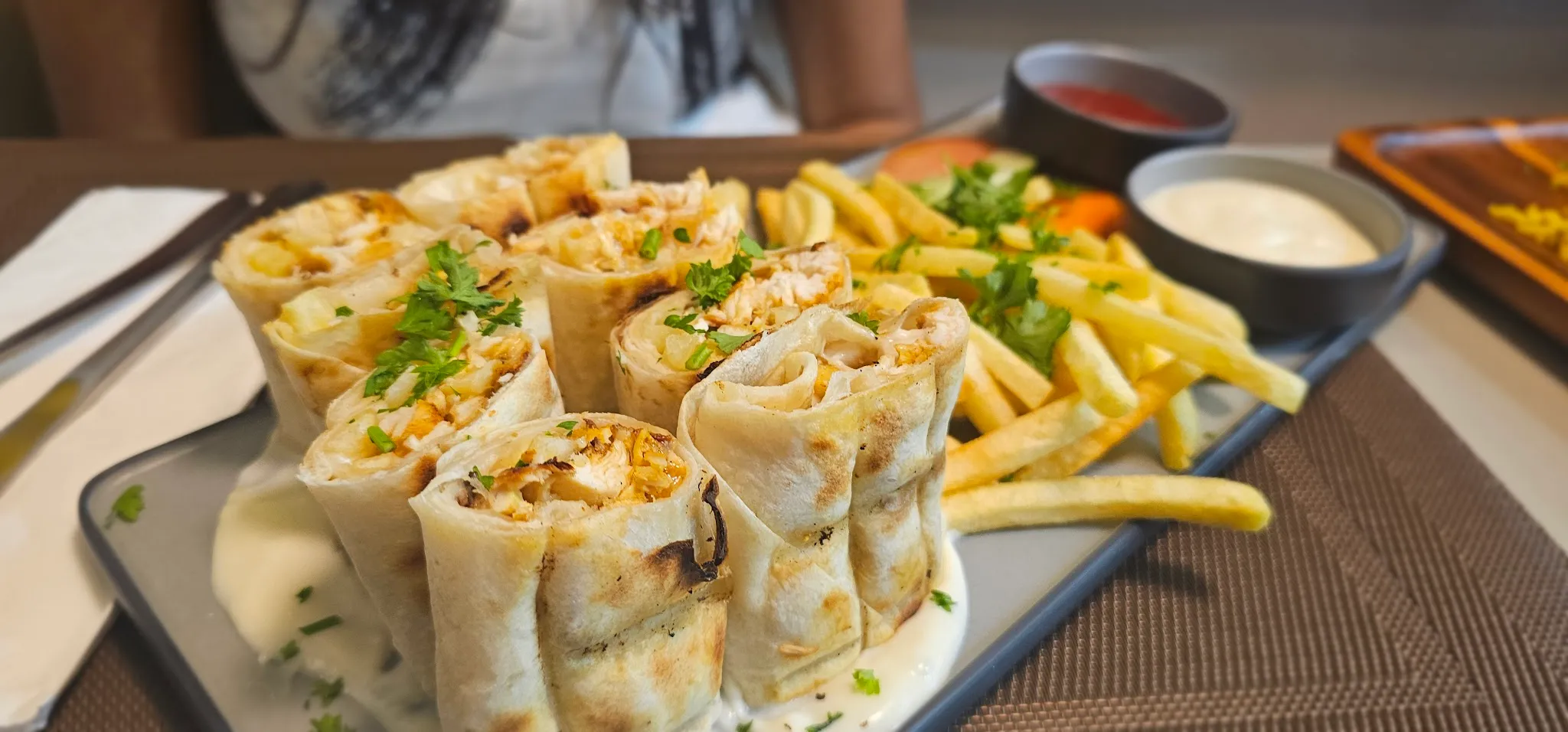 Chicken shawarma rolls on garlic-yogurt sauce with fries